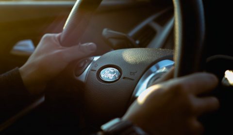 person holding Ford steering wheel