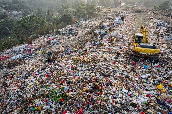 Yellow excavator in garbage mountain