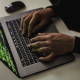 Crop cyber spy hacking system while typing on laptop