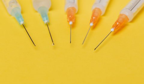 Syringe needles with no cover on yellow background