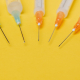 Syringe needles with no cover on yellow background