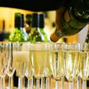 A waiter pouring champagne into a group of glasses, with more bottles out of focus in the background.