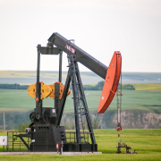A pump jack sits in the middle of a Canola Field on the banks of the Red Deer River valley.