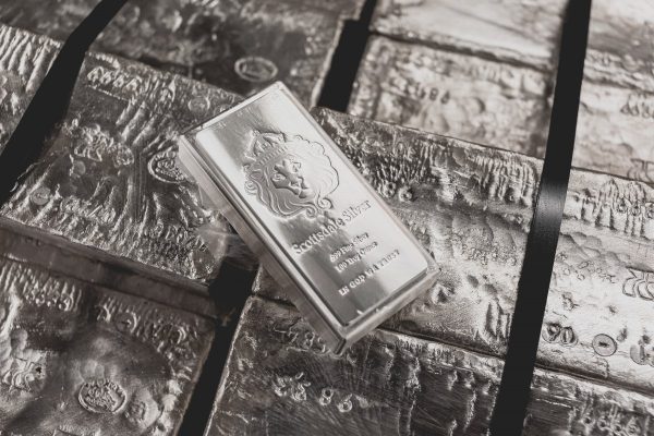A Scottsdale Mint stacker bar sits on top of a pallet of raw silver.