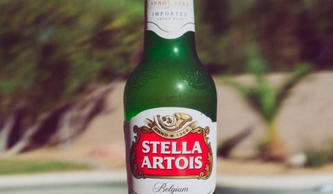 selective focus photography of Stella Artois bottle on beside pool