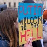 A person holding a placard that says putin welcome to the hell