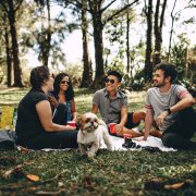 Group of people sitting on white mat on grass field