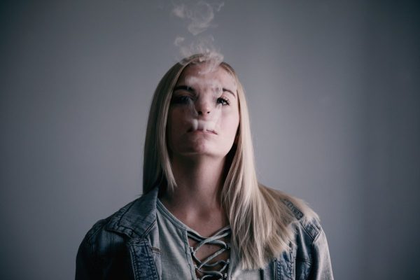 A twenty-four year old young woman blowing smoke after using her e-cigarette.