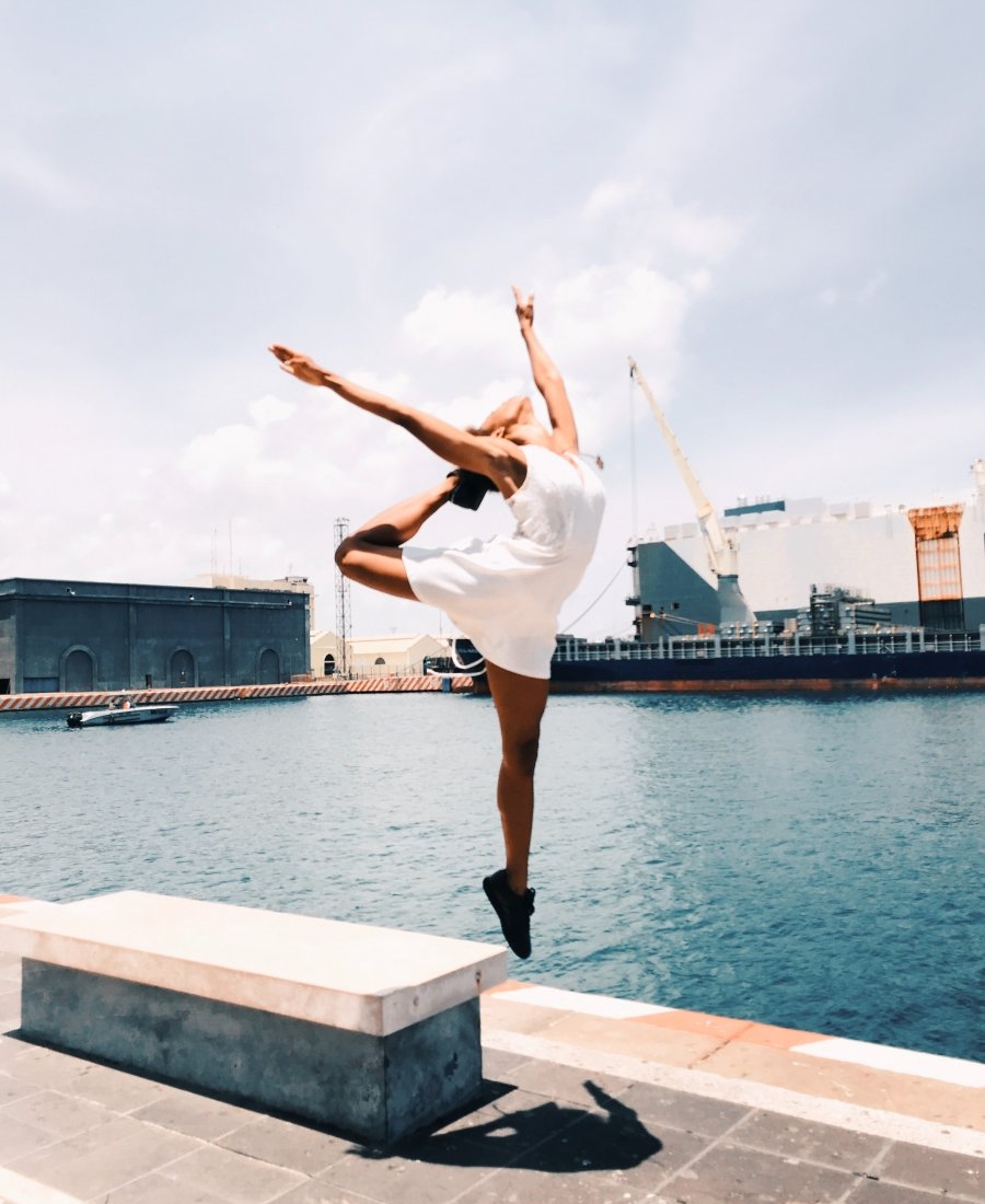 woman jumping in mid-air near body of water during daytime