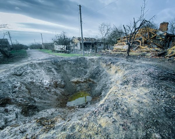 Crater on the dirt ground near the destroyed houses