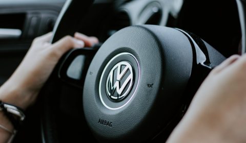 person holding black Volkswagen steering wheel in closed-up photo