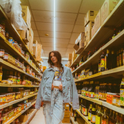 Girl in denim jacket and jeans walking along shop shelves