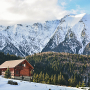 brown wooden house near snow covered mountain during daytime
