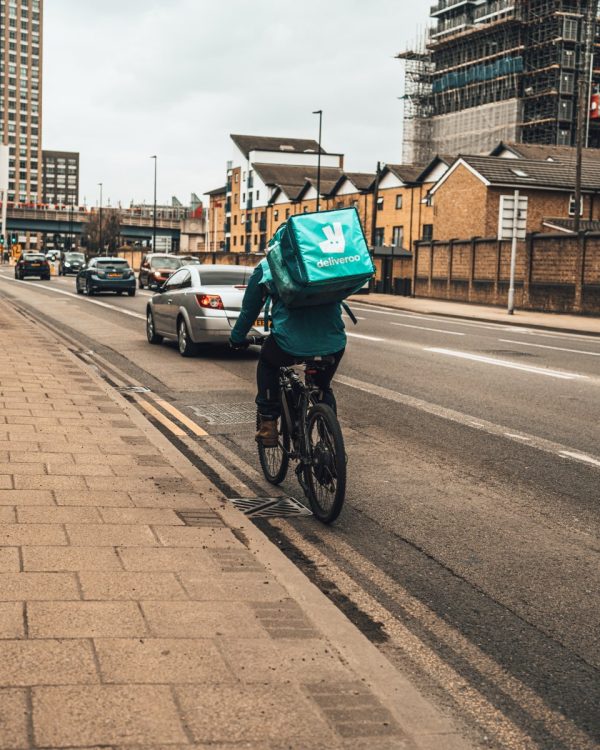 person in green jacket riding bicycle on road during daytime