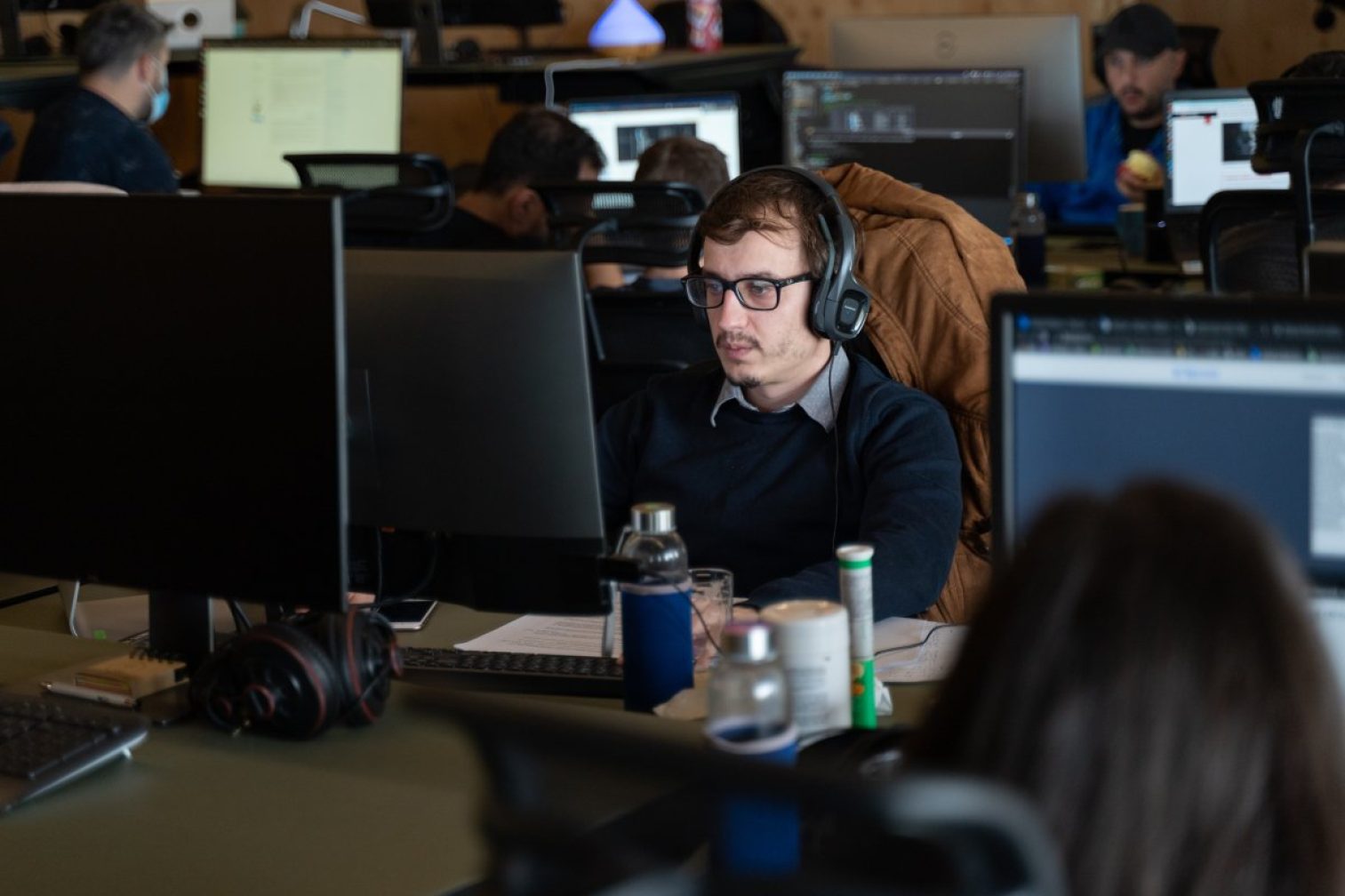 Man wearing glasses and headphone working from office desk.