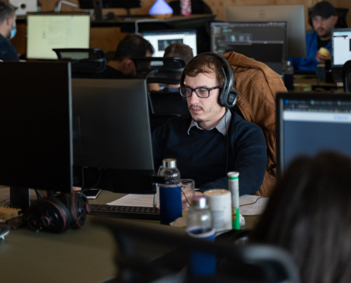 man-wearing-glasses-and-headphone-working-from-office-desk-stockpack-unsplash.jpg Man wearing glasses and headphone working from office desk.