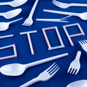 The word stop made of plastic tubes on a blue background with plastic utensils environmental pollution concept. Top view