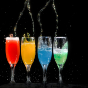 Four champagne flutes with assorted color liquids