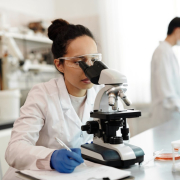Female scientist in white lab coat using a microscope