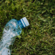 Crushed plastic bottle on green park grass