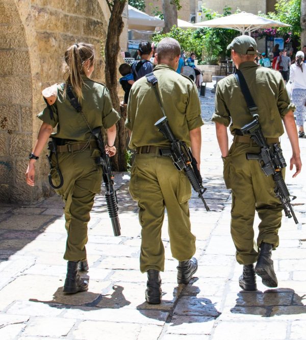 Israeli soldiers walking around a plaza with tourists all around.