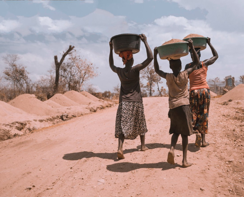 three women carrying basin while walking barefoot
