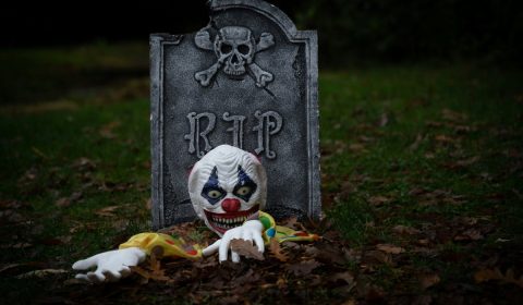 A ghoulish clown escaping from a grave.