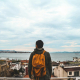 Man wearing black jacket and brown backpack