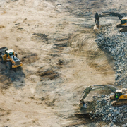 Three yellow excavators near front end loader