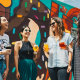 four women holding drinks while laughing together during daytime