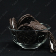 A bowl of Cookies isolated on black background. Chocolate cookies with white cream filling on white bowl