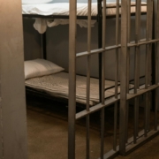 A bunk bed with striped linen behind bars