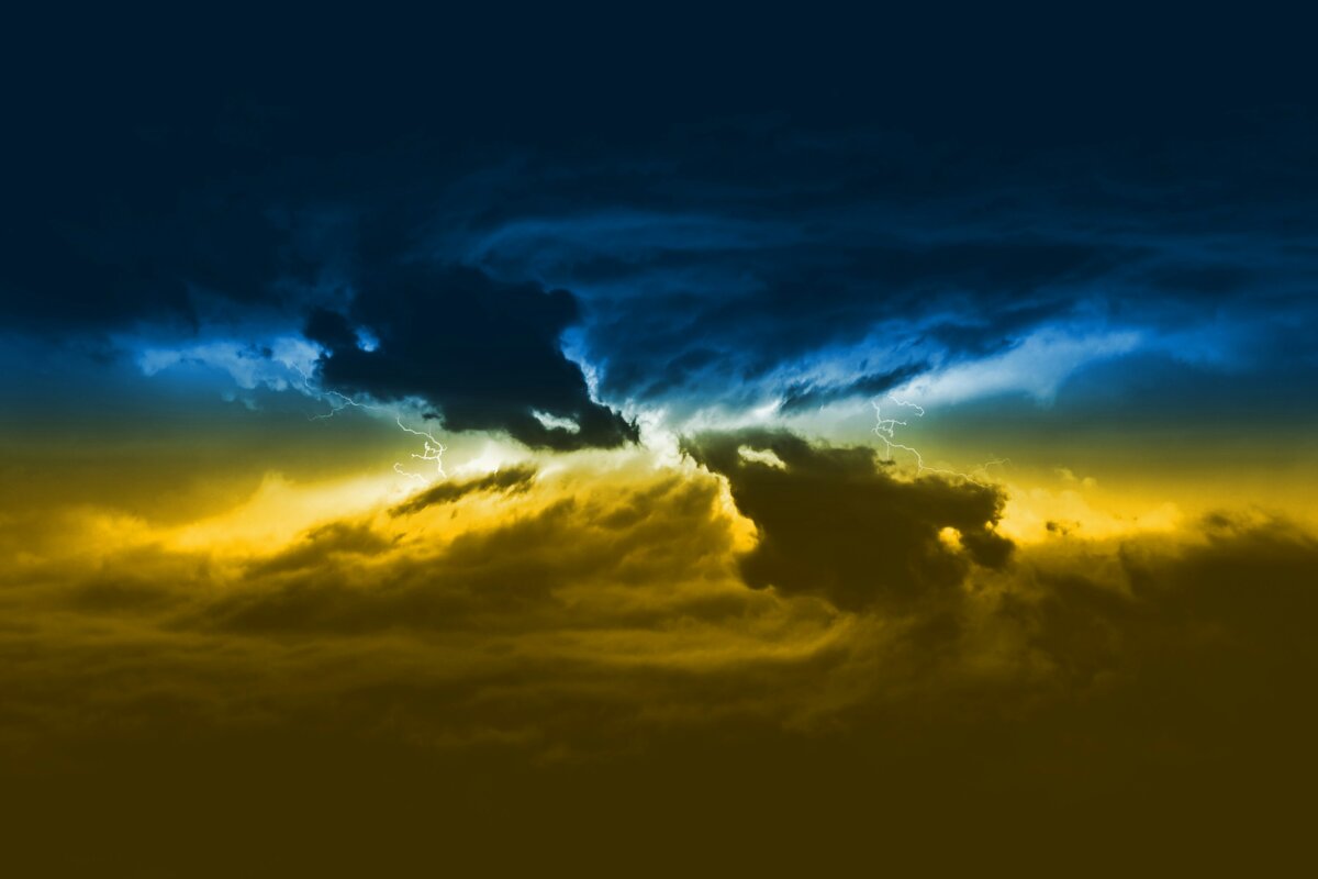 Massive clouds with thunder and lightning discharges of yellow-blue color. Ukrainian flag