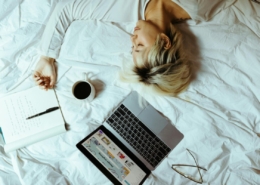 Student sleeping on bed near laptop and cup of coffee