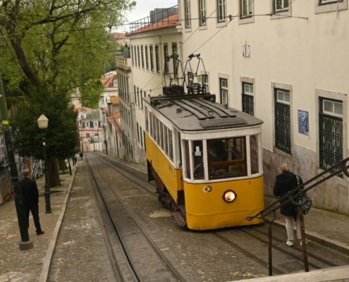 a-yellow-trolley-car-traveling-down-a-street-next-to-a-tall-white-building-stockpack-unsplash.jpg