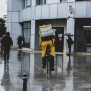 Man in yellow raincoat riding bicycle in front of building