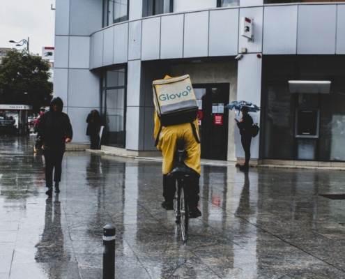Man in yellow raincoat riding bicycle in front of building