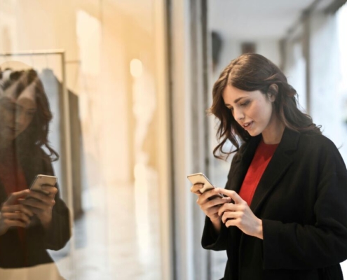 Close up photo of woman in black coat using smartphone