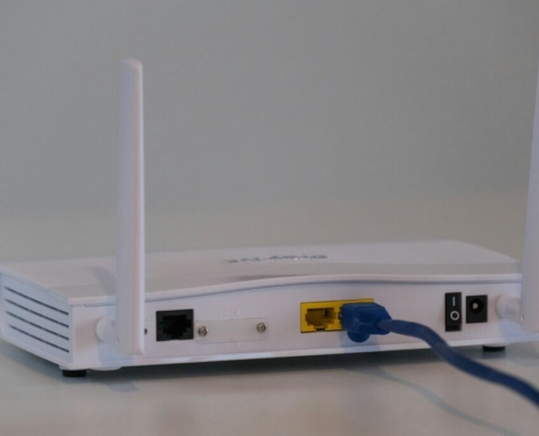 Broadband internet router with ethernet cable plugged in to the back in the ethernet port.