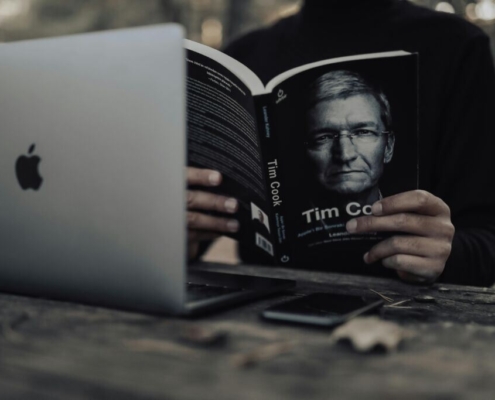 Crop man with laptop reading book