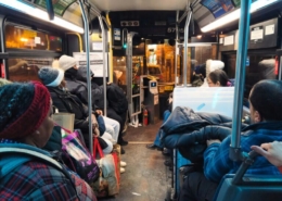 Inside a Jersey City bus at night, the interior is filled with daily commuters heading home after a long day. The bus, lit by the soft glow of overhead lights, captures the typical urban transit experience, with passengers seated.