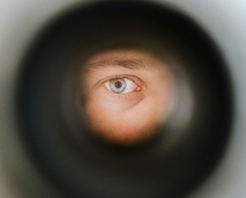 A green eye observing the outside world through a peephole in Berlin.